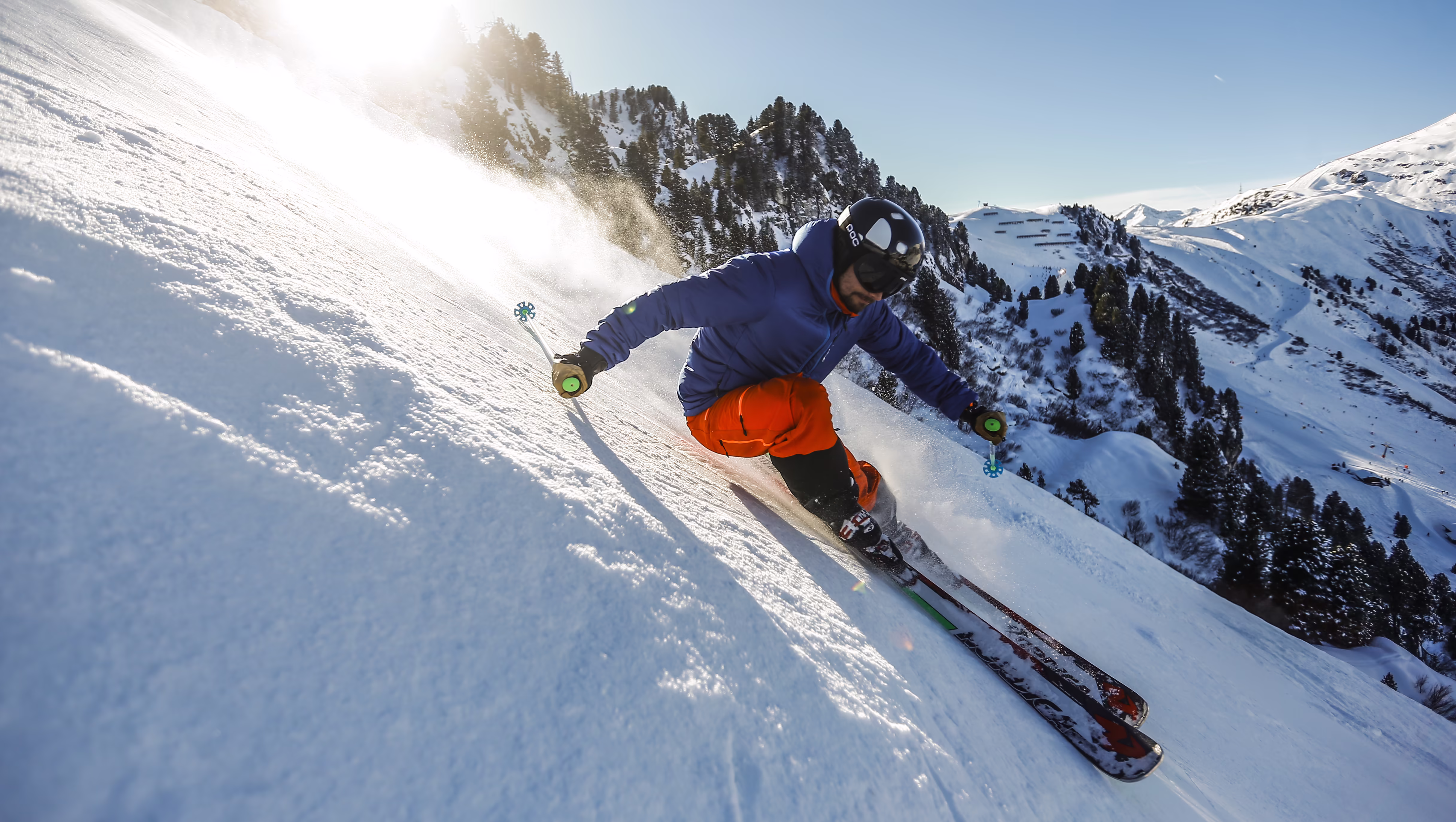 Skifahrer carvt auf der Piste bei Sonnenschein